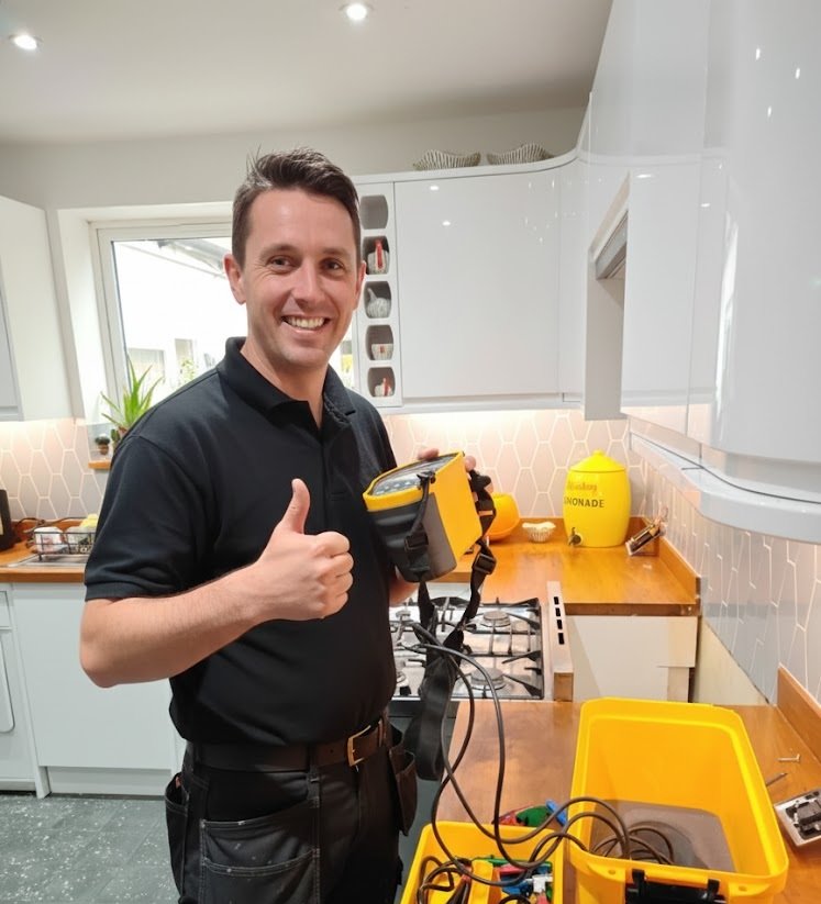 Electrician giving a thumbs-up beside test equipment after an inspection