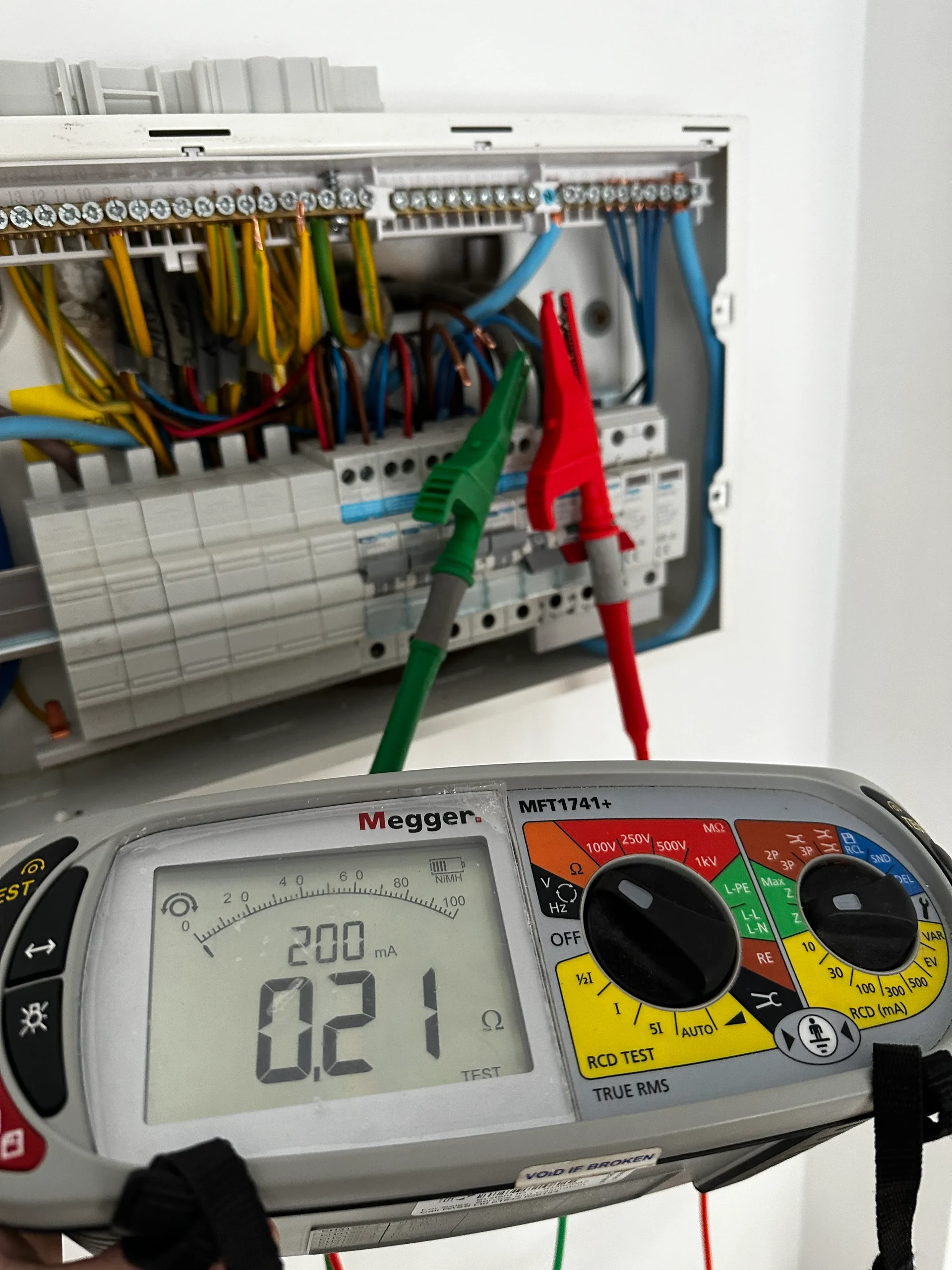 Electrician repairing wiring inside an under-stairs meter cupboard